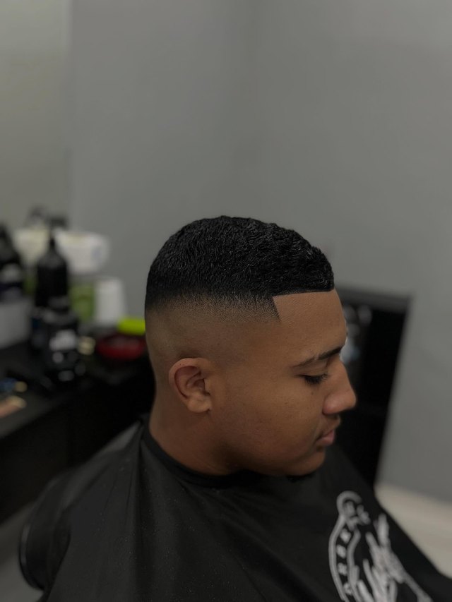 Perfil de um corte degradê baixo, contorno da testa marcado a navalha.